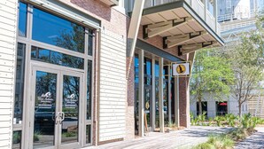 A building with large glass windows, a wooden deck, and a sign indicating a medical facility. - Tropical Treat | Walk to Beach, Pool, & Resort (Port St. Joe)