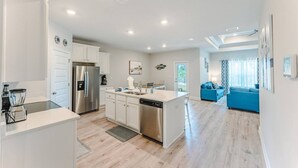 A modern kitchen with white cabinets, stainless steel appliances, and a central island. - Tropical Treat | Walk to Beach, Pool, & Resort (Port St. Joe)