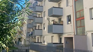 A multi-story residential building with balconies, a clear sky, and a fence in the foreground. - Alessia's Flat - Borgo Palazzo 005 (Bergamo)
