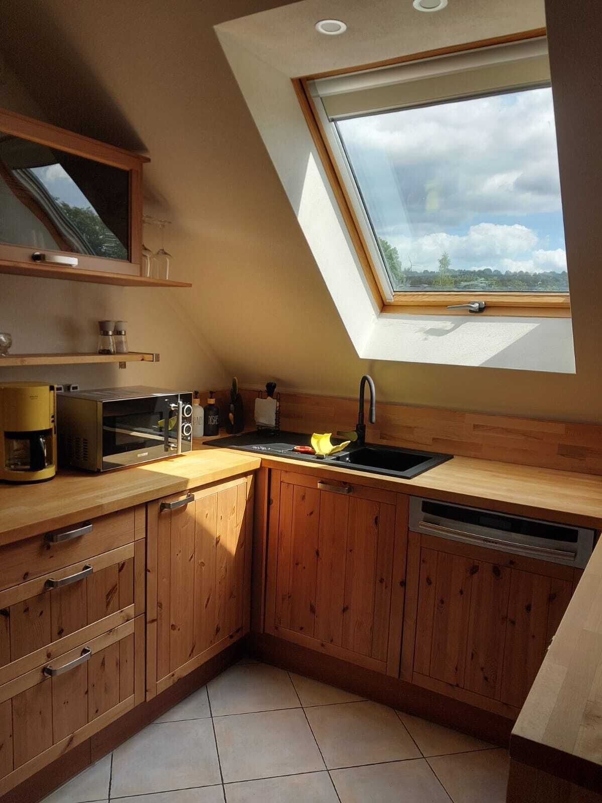 Una cocina con armarios de madera, horno empotrado, cafetera y tragaluz.