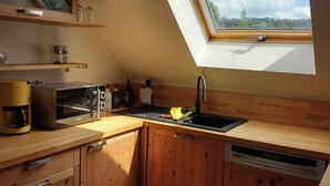 Una cocina con armarios de madera, horno empotrado, cafetera y tragaluz.