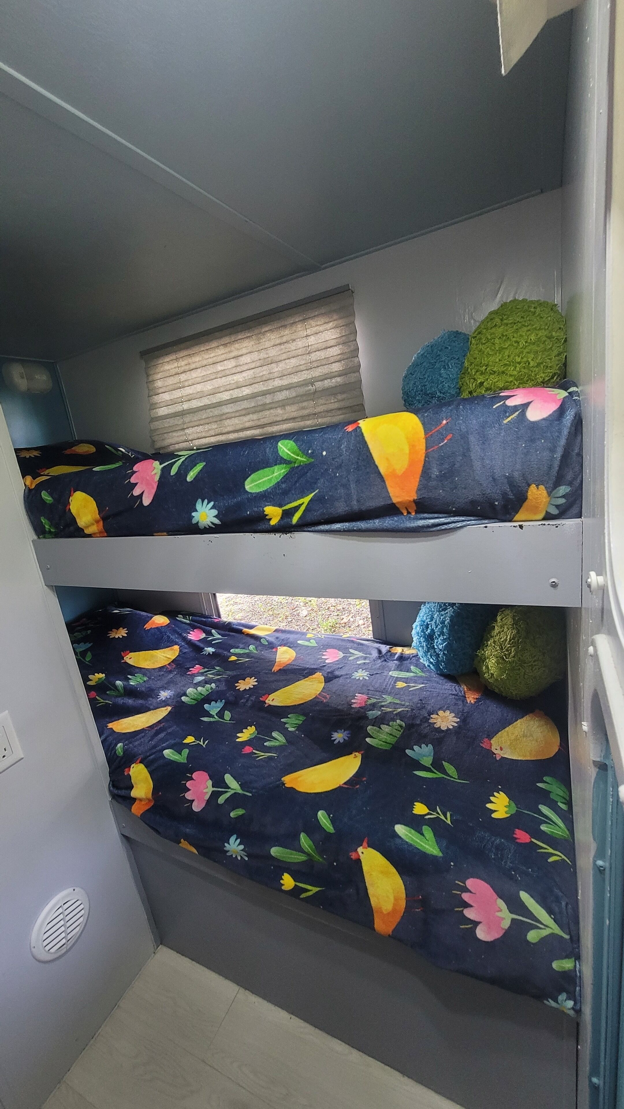 A bunk bed with colorful bedding featuring birds and flowers.