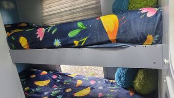 A bunk bed with colorful bedding featuring birds and flowers.