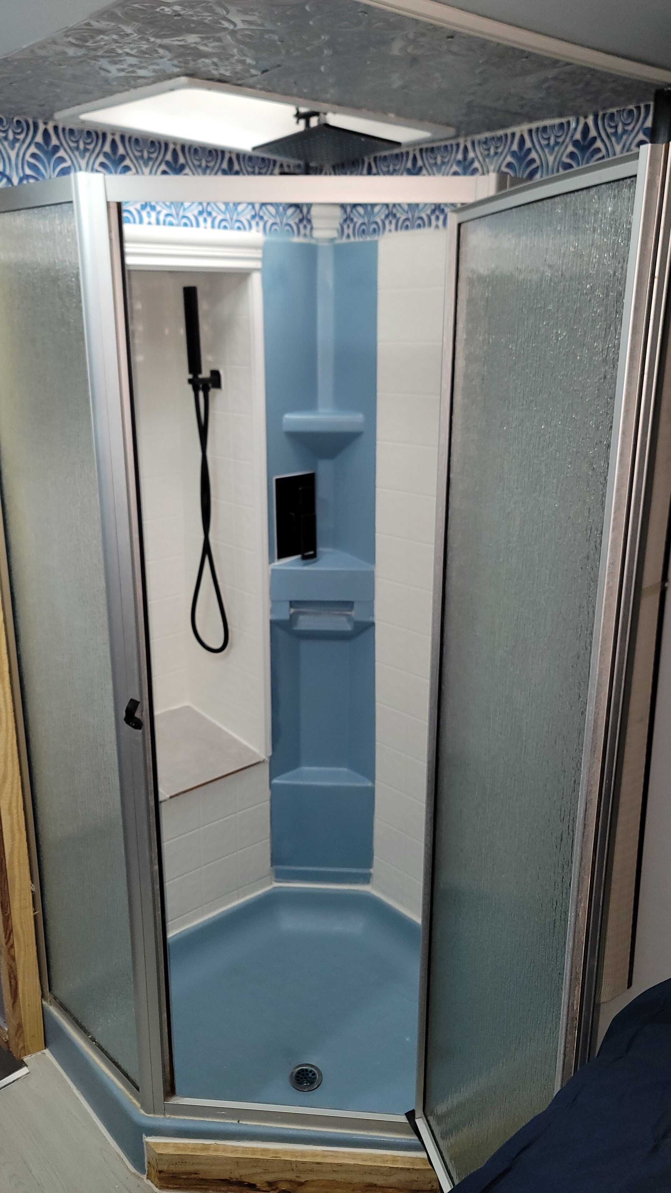 A small, enclosed shower area with a glass door and a blue interior.