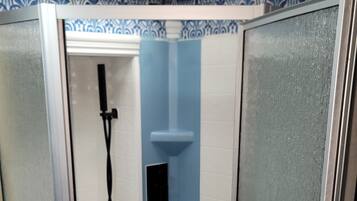 Un espacio de ducha pequeño y cerrado, con puerta de cristal y revestimiento azul.