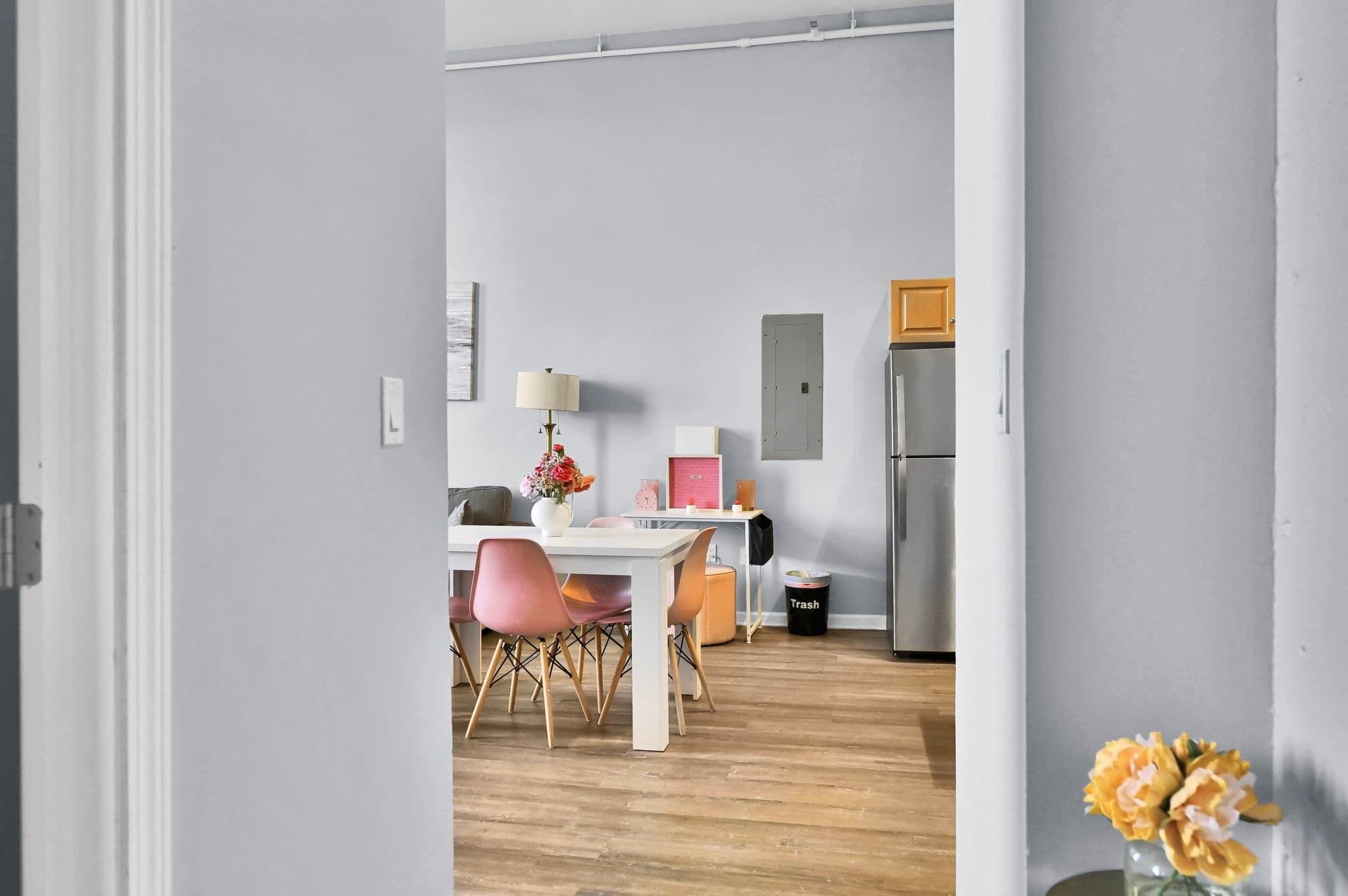 Eine moderne Küche mit weißer Arbeitsplatte, einem Edelstahl-Kühlschrank und einem Essbereich mit weißem Tisch und rosa Stühlen.