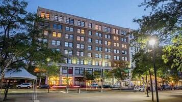 Ein mehrstöckiges Hotel mit moderner Fassade, großen Fenstern und einem Parkplatz davor.