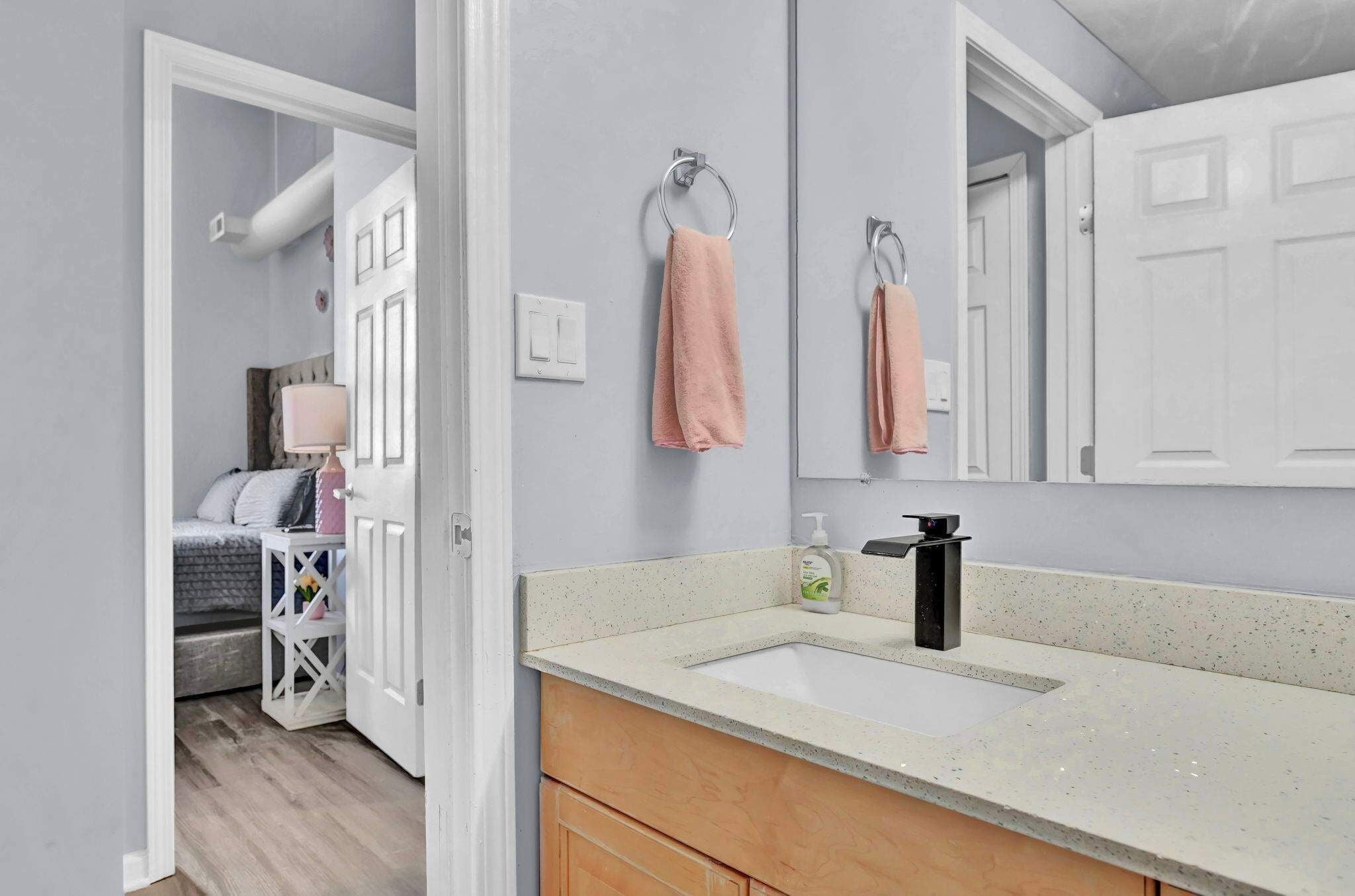 A bathroom with a white sink, a mirror, and a towel rack.
