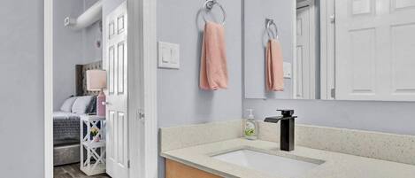A bathroom with a white sink, a mirror, and a towel rack.