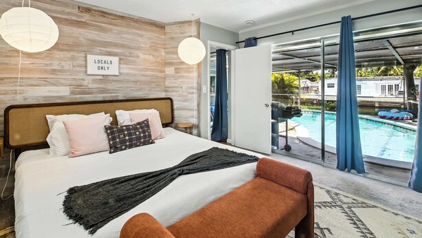 A bedroom with a large bed, a view of a swimming pool, and a sign that reads "Locals Only". - Tranquil Waterfront • Enclosed pool • Kayaks (Oakland Park)