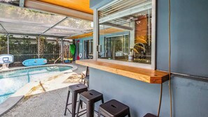 An outdoor pool area with a wooden bar and stools, a basketball hoop, and a blue inflatable pool. - Tranquil Waterfront  • Enclosed pool • Kayaks (Oakland Park)