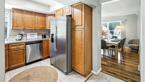A modern kitchen with wooden cabinets, stainless steel appliances, and a dining area with a wooden floor. - Tranquil Waterfront • Enclosed pool • Kayaks (Oakland Park)