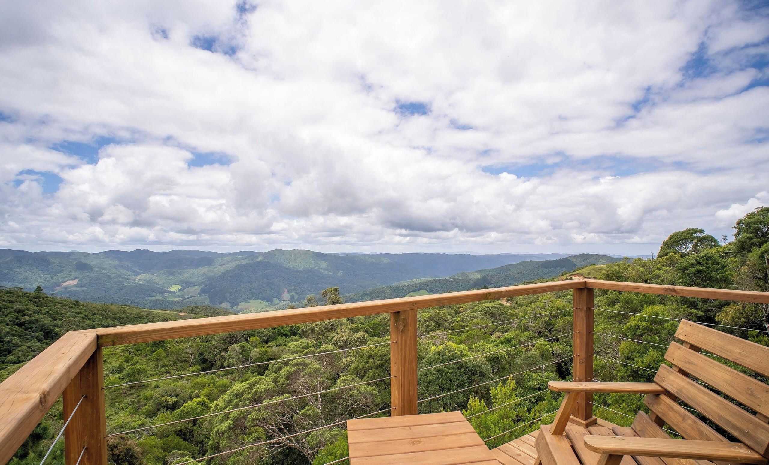 A wooden deck with a railing overlooking a mountainous landscape.