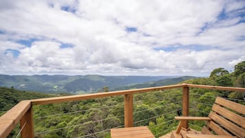 A wooden deck with a railing overlooking a mountainous landscape.