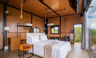 Habitación de hotel moderna con una cama grande, paredes de madera, un escritorio pequeño y una ventana con vistas al exterior.