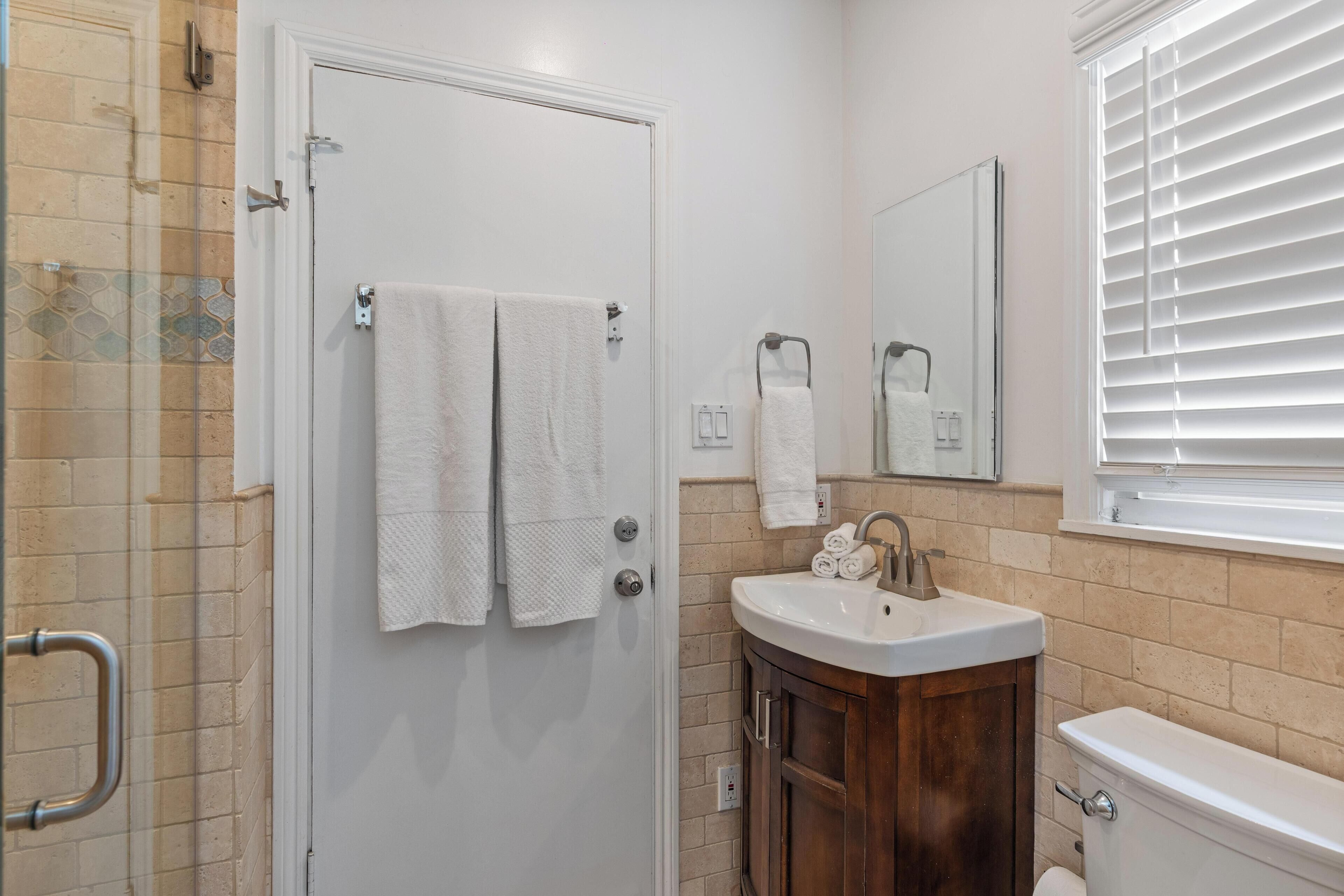 A bathroom with a white door, a sink with a mirror above it, and a toilet.