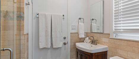 A bathroom with a white door, a sink with a mirror above it, and a toilet.