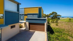A modern building with a flat roof, a garage, and a clear view of the ocean. - Saltwater Apartments - 2 Bedroom (Eden)