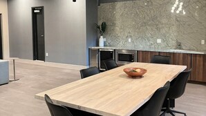 Moderni kokoushuone, jossa on puinen pöytä, mustat tuolit ja marmorista tehty seinäpaneeli.