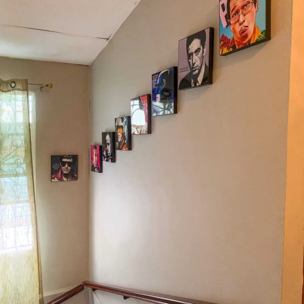 Um corredor com várias quadros na parede, um corrimão de madeira e uma janela com cortina.