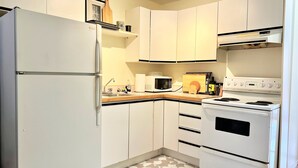 Eine Küche mit weißen Schränken, einem Kühlschrank, einer Mikrowelle und einem Herd.