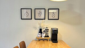 Eine kleine Küche mit einem Holztisch, einer Kaffeemaschine und gerahmten Bildern an der Wand.