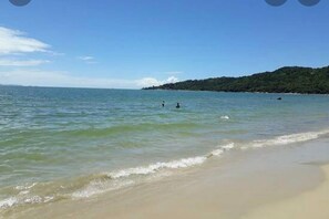 A beach with clear water and a distant hill.