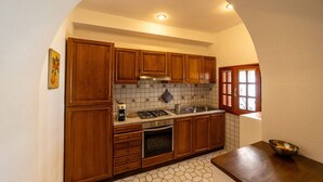Una cocina con armarios de madera, estufa a gas y salpicadero de azulejos.