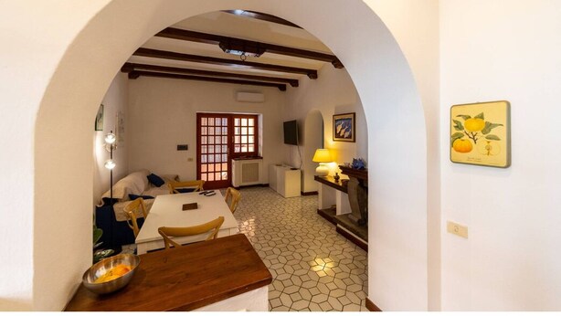 Un comedor con una mesa blanca, sillas y una encimera de madera. Hay una ventana que ofrece vistas al exterior.