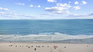 A beach with people and umbrellas.