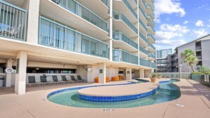 A hotel with a pool area, outdoor seating, and a covered lounge.