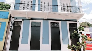 A two-story building with a balcony, large windows, and a door.