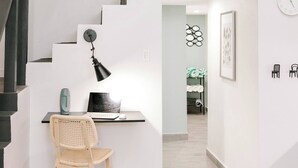 A staircase with a black handrail leading to a landing with a desk, chair, and a wall-mounted lamp.