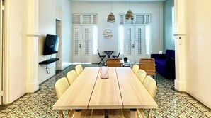 A dining area with a long wooden table, wicker chairs, and hanging pendant lights.