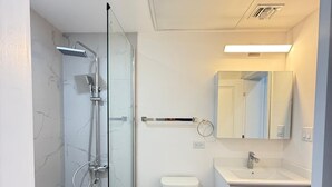 A modern bathroom with a glass-enclosed shower, a toilet, a sink, and a mirror. - Charming Apartment in Gorgeous George Town with GYM, Pool, and Pickleball Court (George Town)