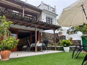 Una veranda con tavolo e sedie, una zona riparata e piante in vaso.