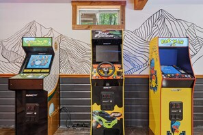 Drie speelautomaten tegen een muur met een bergdecoratie.