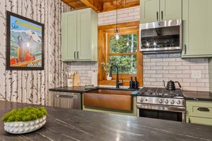 A kitchen with a stove, sink, and window. - Family Retreat • Sauna • Hot Tub • Games • Peloton (Bartlett)