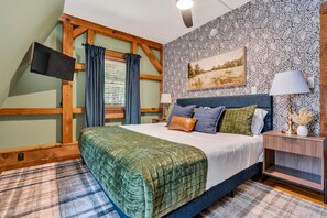 A bedroom with a bed, a nightstand, a lamp, a painting on the wall, and a window with curtains. - Family Retreat • Sauna • Hot Tub • Games • Peloton (Bartlett)