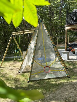 A tent-like structure with a triangular base and a canopy, surrounded by a grassy area with trees in the background. - Family Retreat • Sauna • Hot Tub • Games • Peloton (Bartlett)