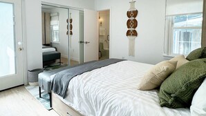 Ein modernes Schlafzimmer mit einem großen Bett, einem Kleiderschrank und einem durchgegangenen Tür sichtbar liegenden Badezimmer.