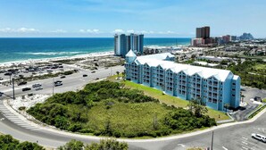 Un hôtel situé sur la côte, doté d’un grand parking, offrant une vue sur la plage et se distinguant par son imposant bâtiment bleu surmonté d’une tour.