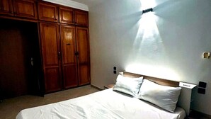 Une chambre à coucher avec un lit, une armoire en bois et une table de chevet.