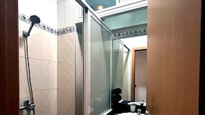 Une salle de bain avec une douche, un lavabo et un miroir.