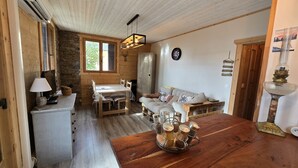 A cozy cabin interior with a wooden dining table, a sofa, and a wooden floor.
