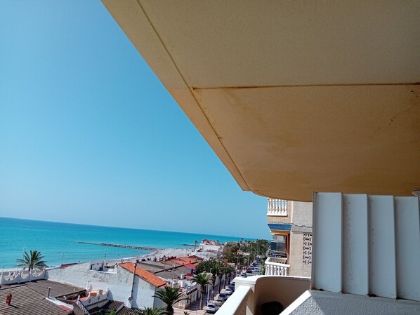 Un balcon avec vue sur une plage, une jetée et une rangée de bâtiments.