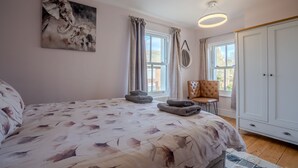 Un dormitorio con cama, una silla, un armario y una ventana.