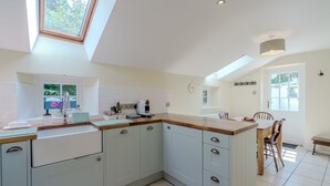 A modern kitchen with a skylight, white cabinets, and a wooden countertop. - Sunny Cottage by East Ruston Cottages (Southrepps)