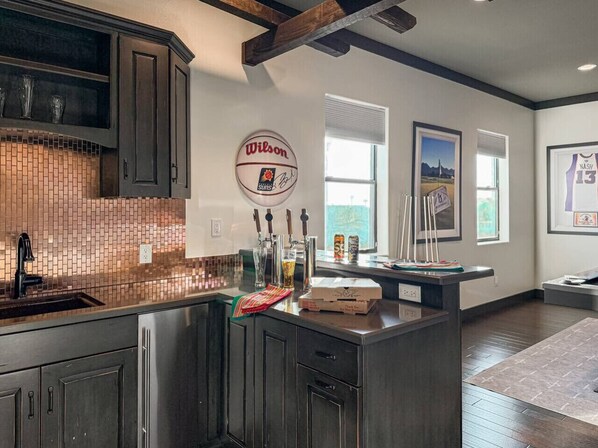 A modern kitchen with dark cabinetry, a tiled backsplash, and a central island. - Sunset Greens - Golf Simulator, Putting Green, Gam (Mesa)