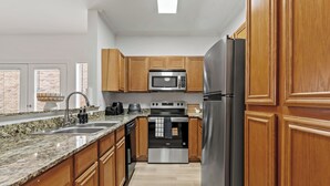 A modern kitchen with wooden cabinets, stainless steel appliances, granite countertops, and a dishwasher.